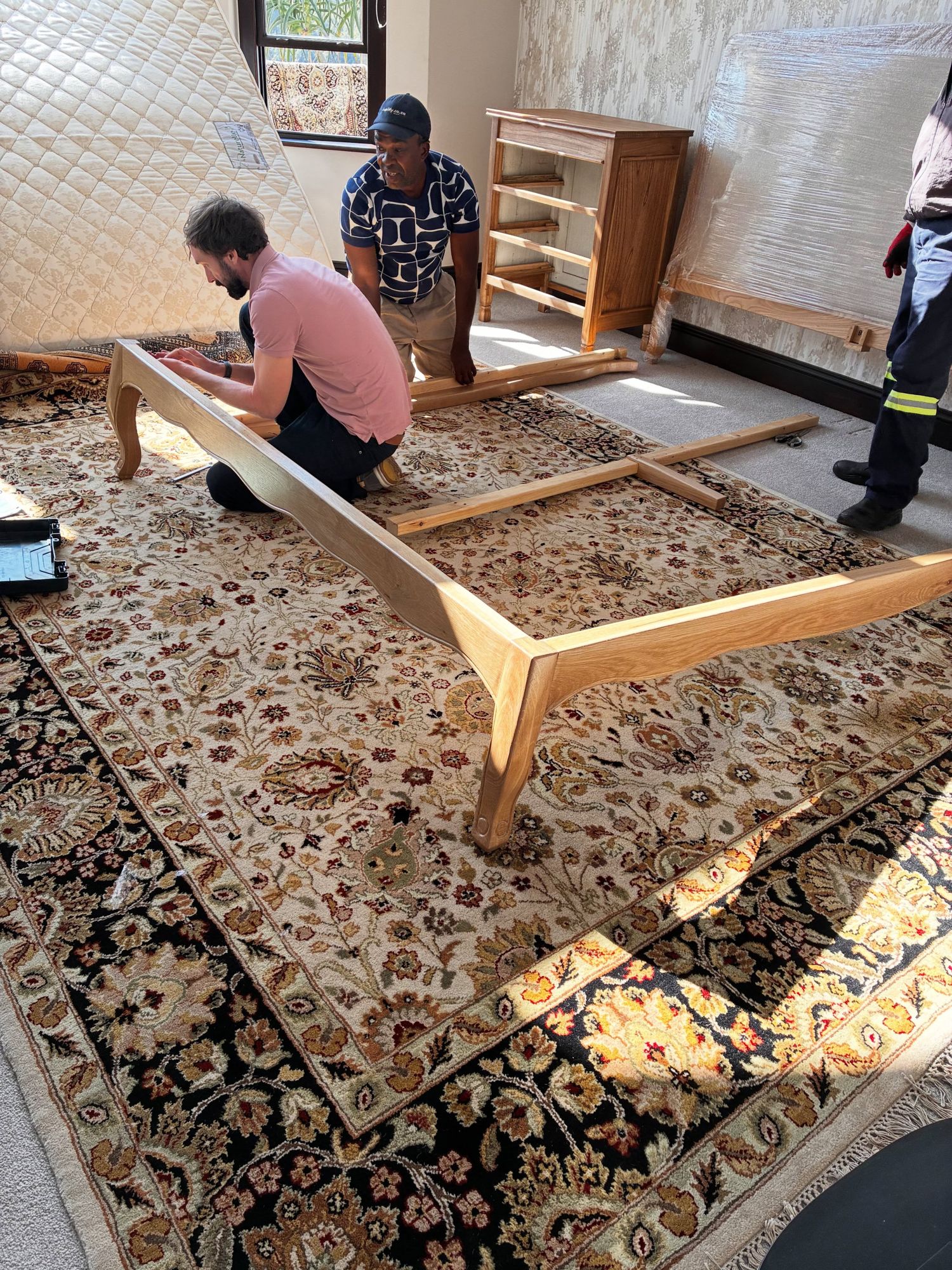 Two people assembling the bed on a rug in the client's room