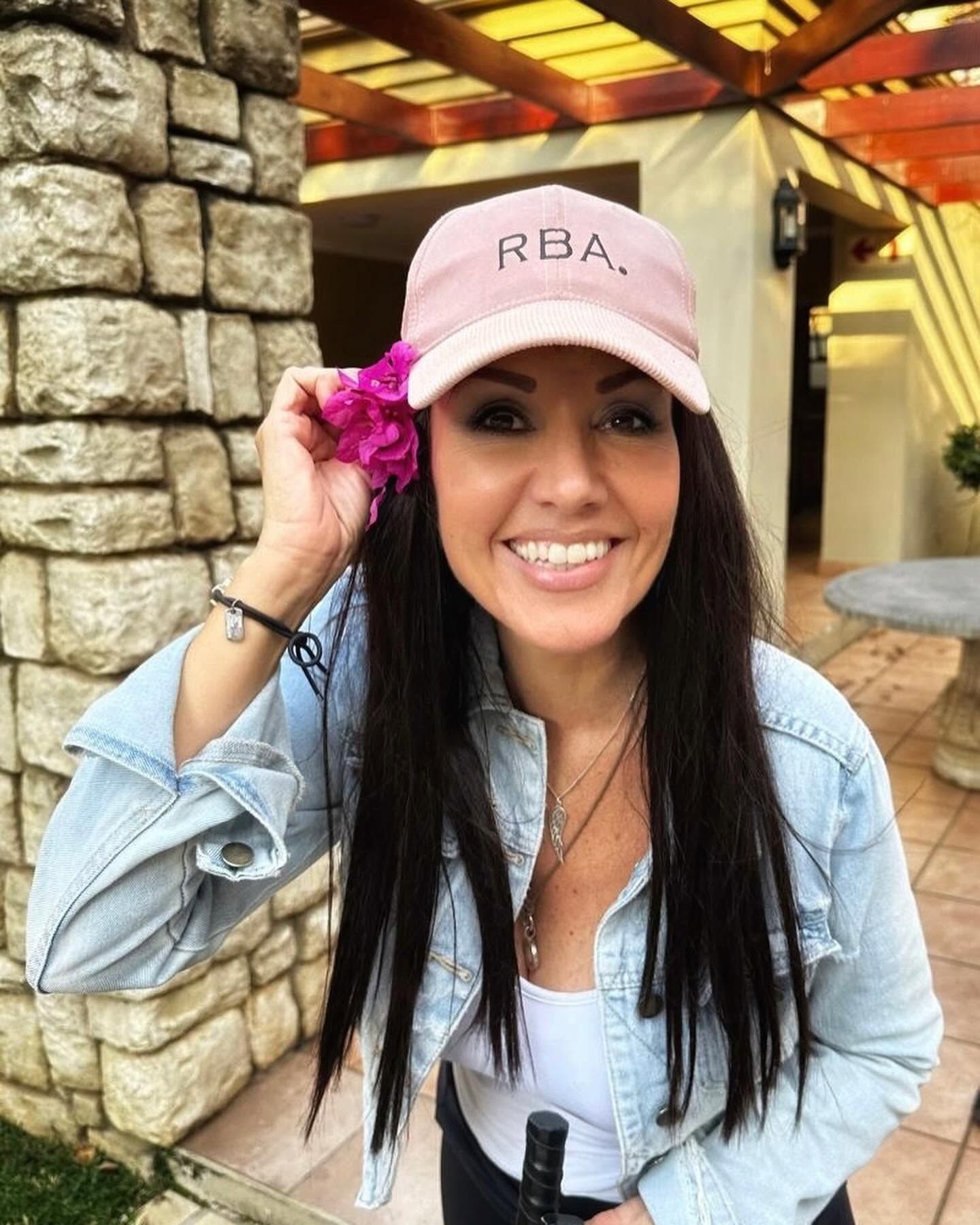 Dian outdoors with a pink flower, smiling