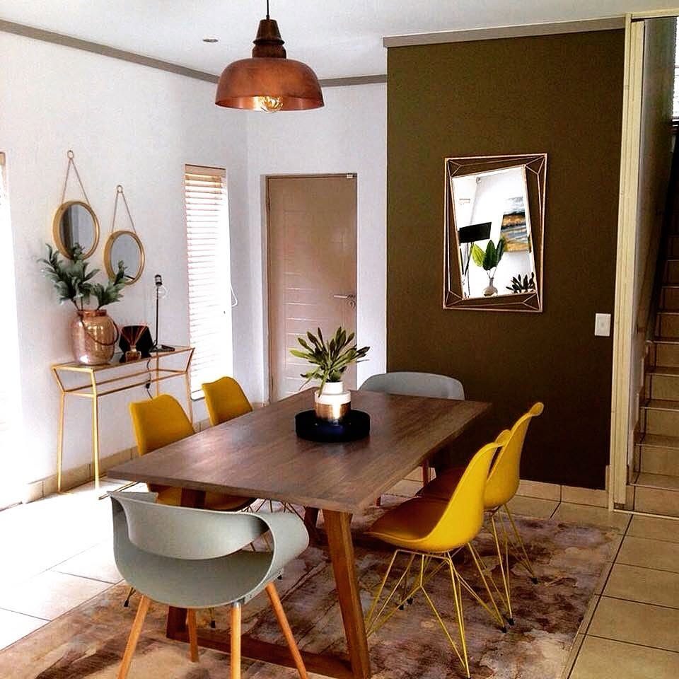 A dining room with yellow chairs and a copper pendant